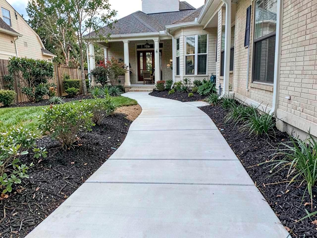 Concrete walkway through a landscaped yard
